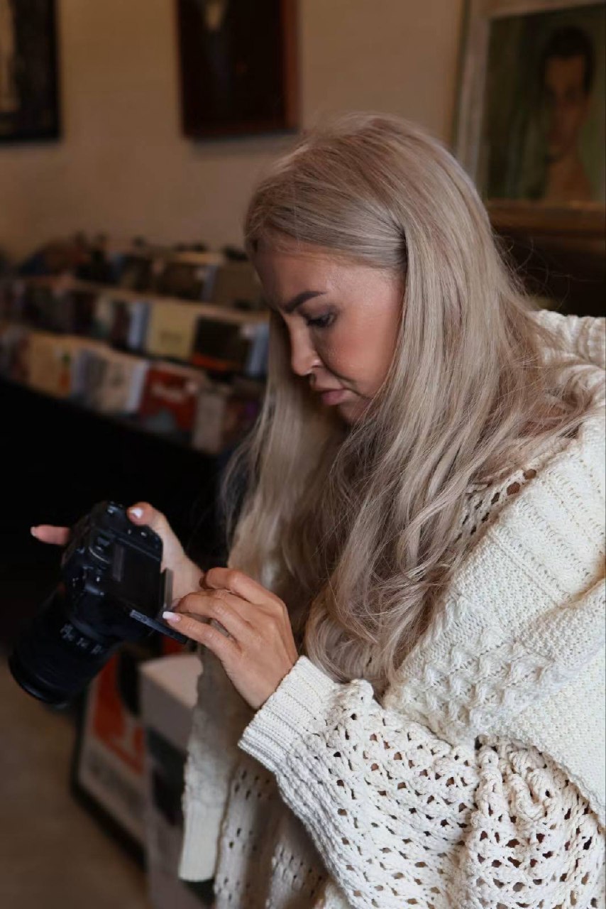 Kate checking a camera inside The Kilmorna Collection, with records and artwork behind her