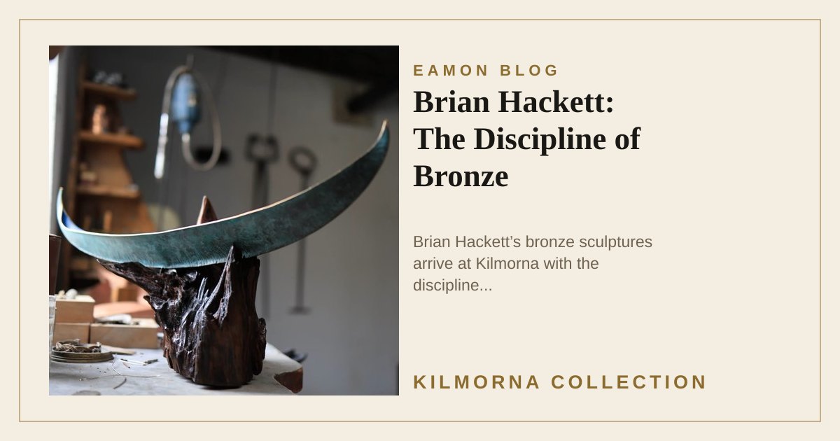 A long curved bronze sculpture resting on a wooden form in Brian Hackett’s studio