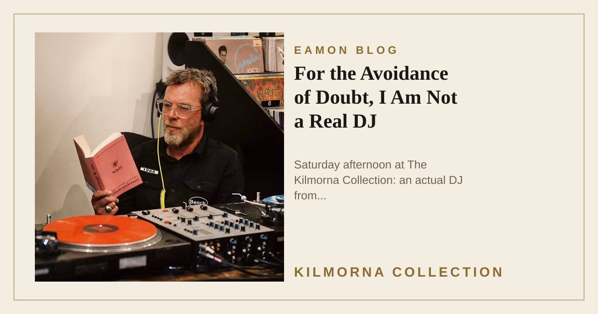 Eamon Lane seated beside DJ equipment inside The Kilmorna Collection, wearing headphones and reading The Quiet Tenant